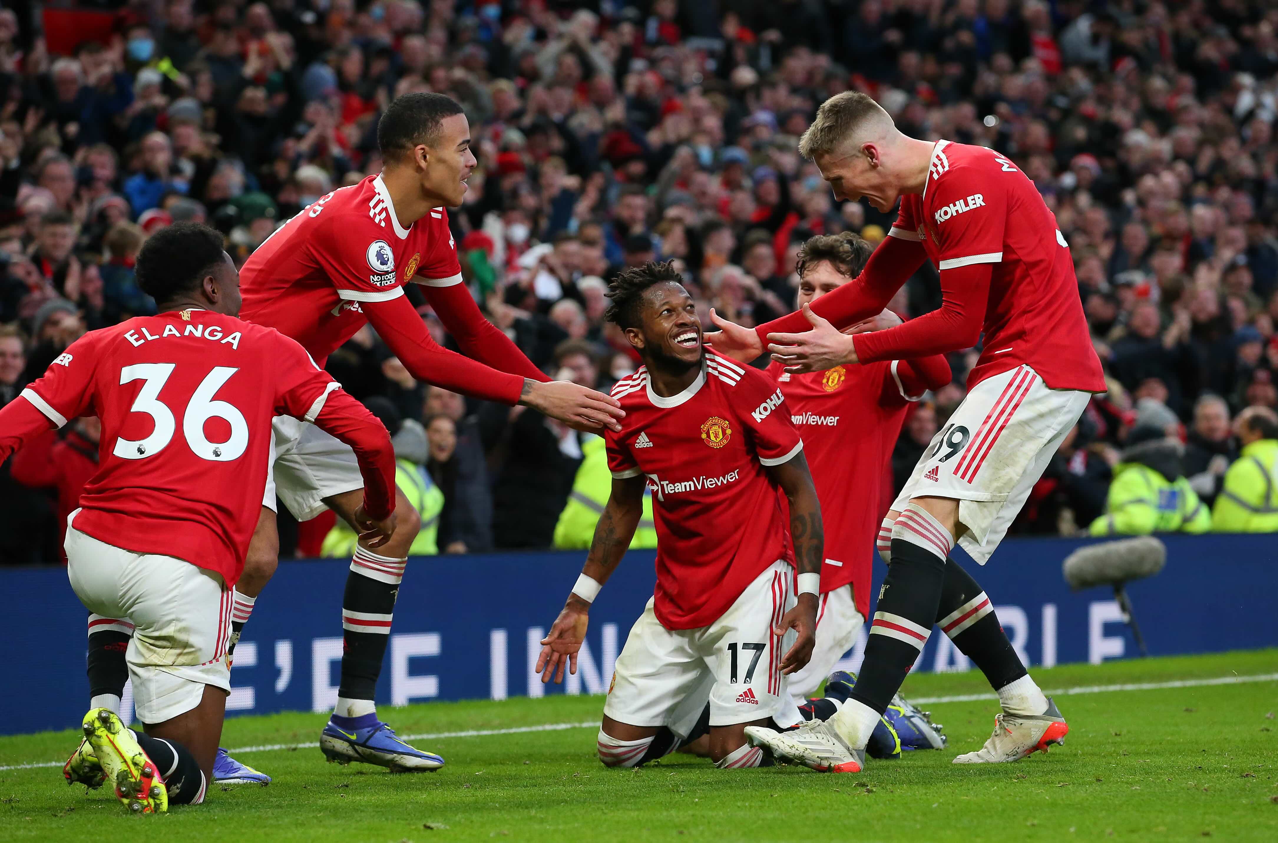 Manchester United players in red shirts celebrate a Premier League goal at Old Trafford in front of their home fans
