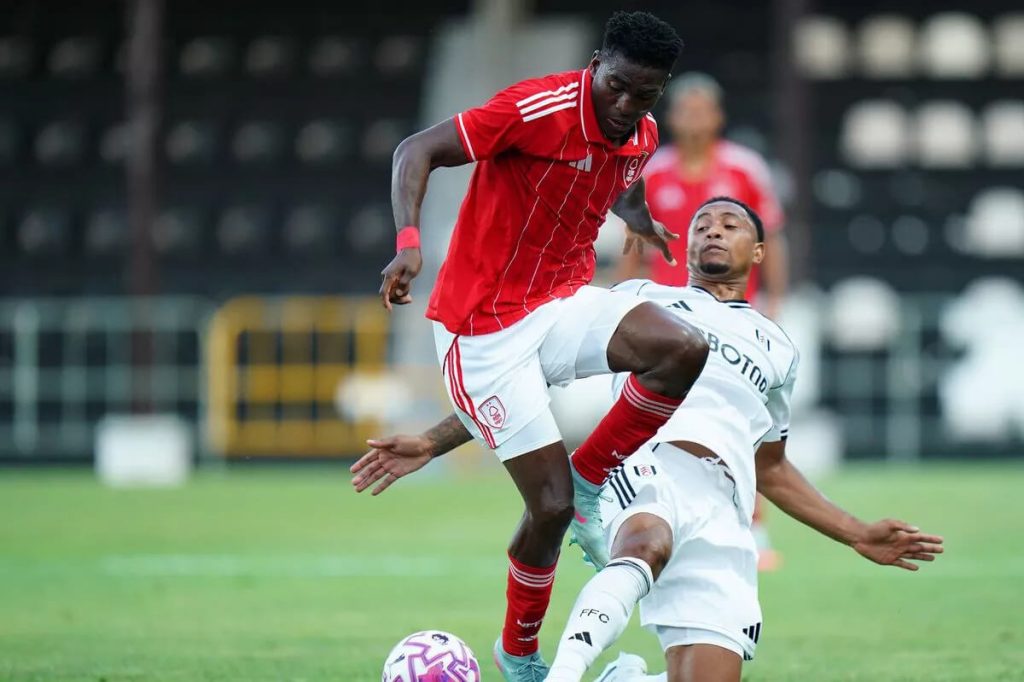 Nottingham Forest player in red challenges Fulham defender in white during Premier League match action